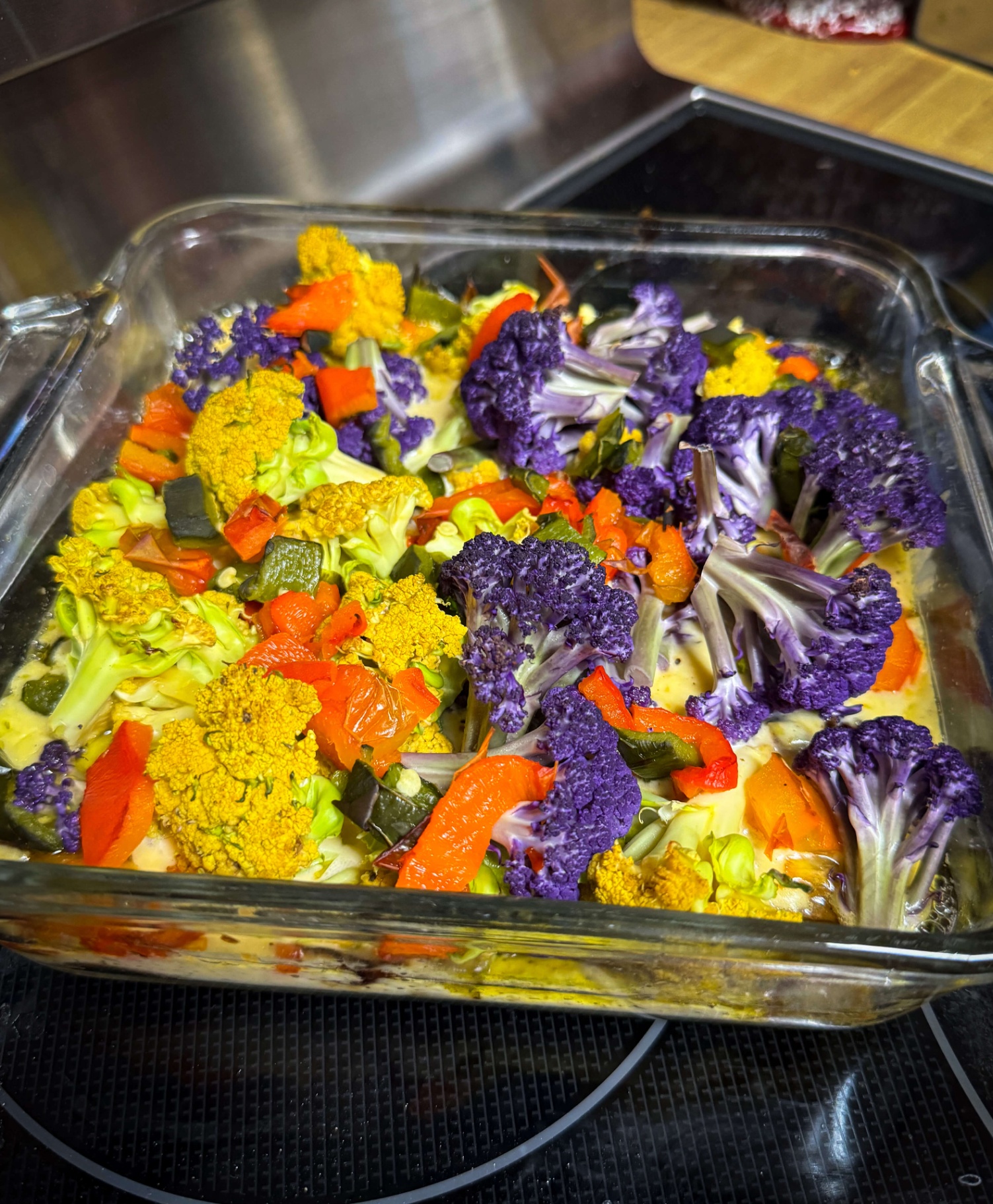 Roasted purple, yellow and green cauliflower with peppers in a glass dish