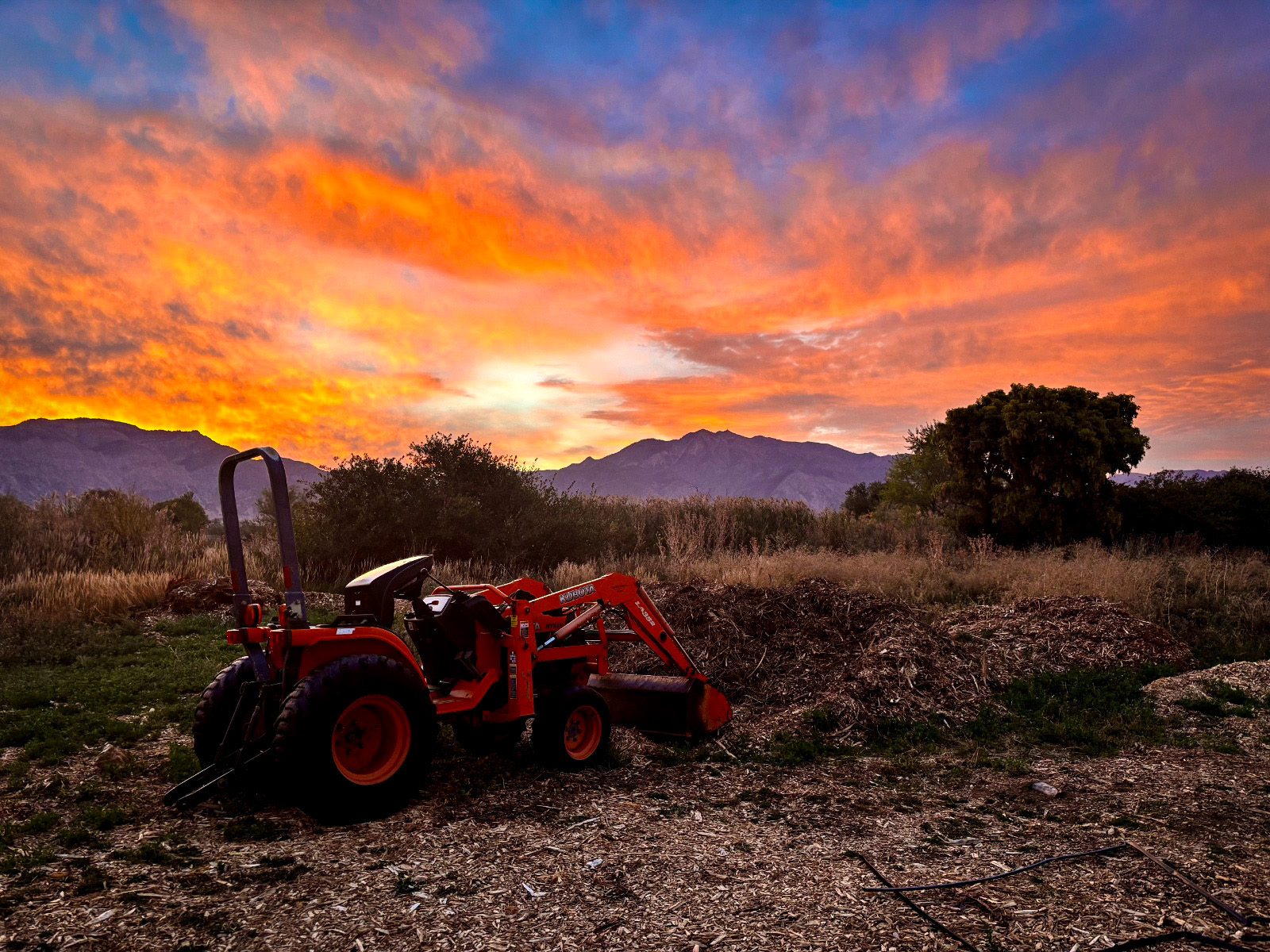 Tractor parked in front of a fiery sunset over the Wasatch mountains