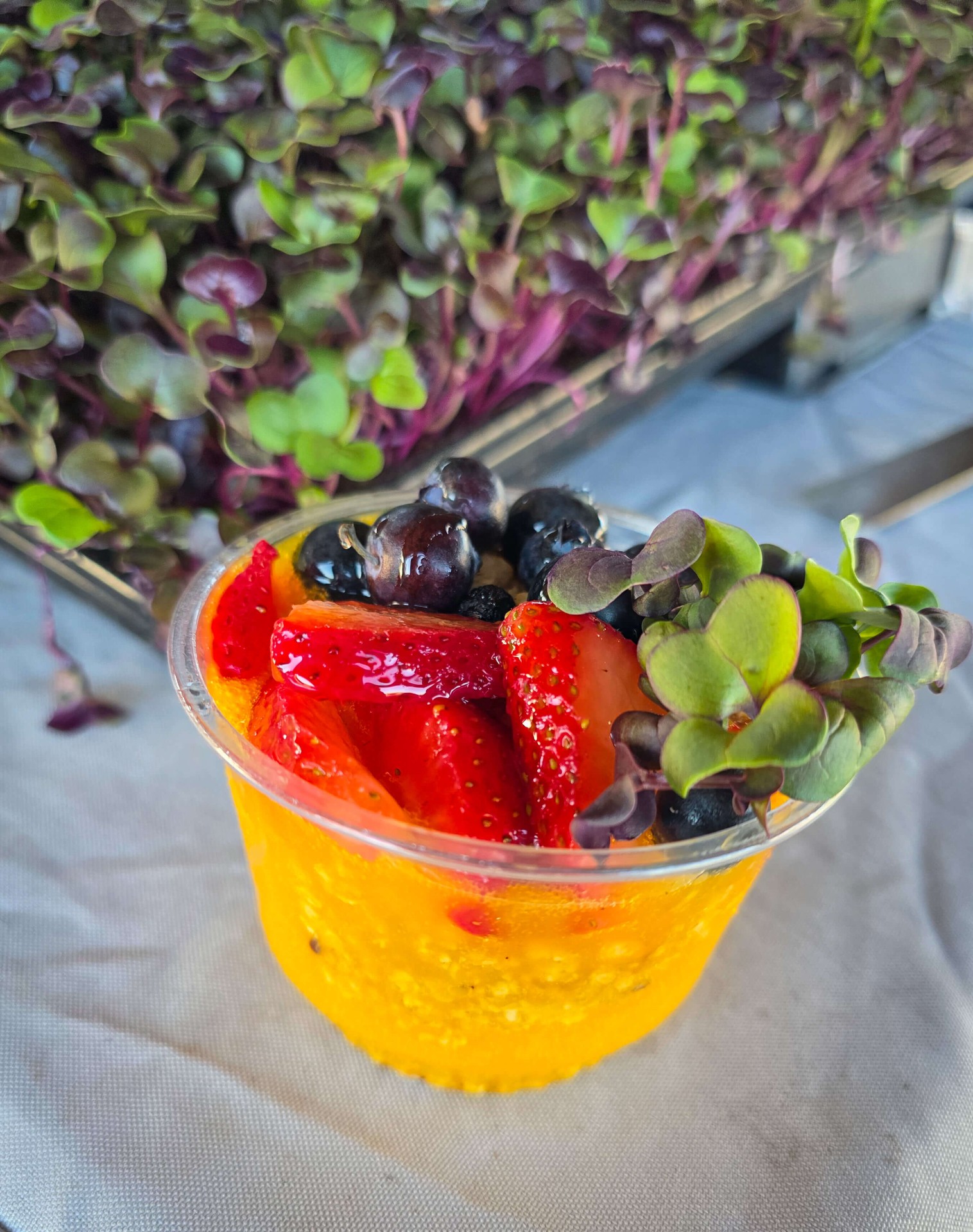 Mango chia cup topped with berries and microgreens