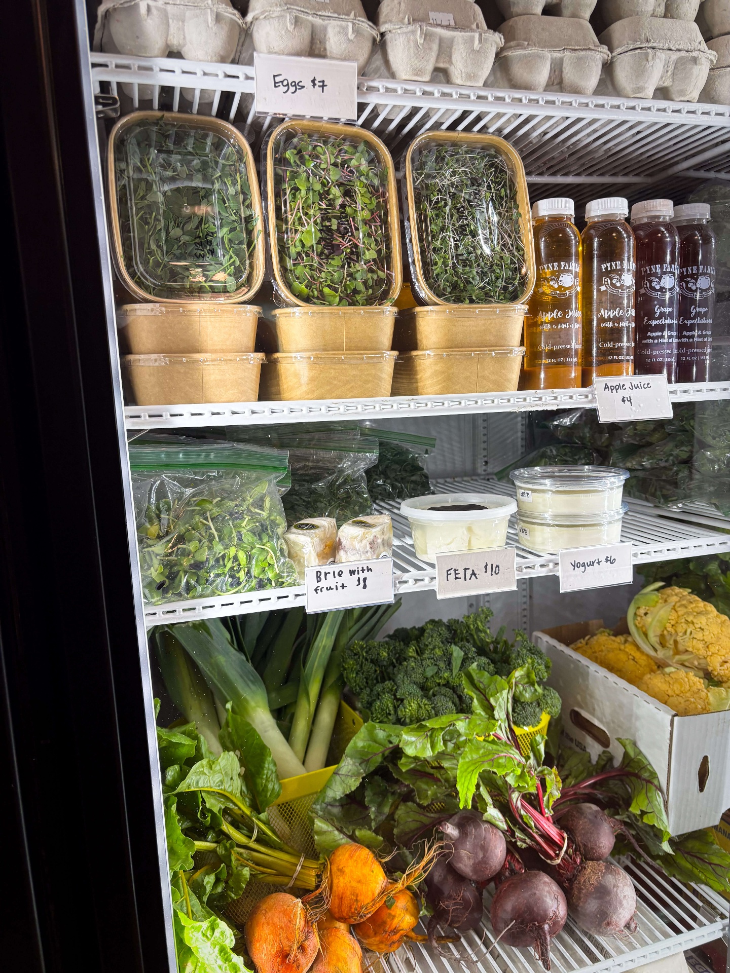 Farm fridge stocked with microgreens, eggs, juice and produce